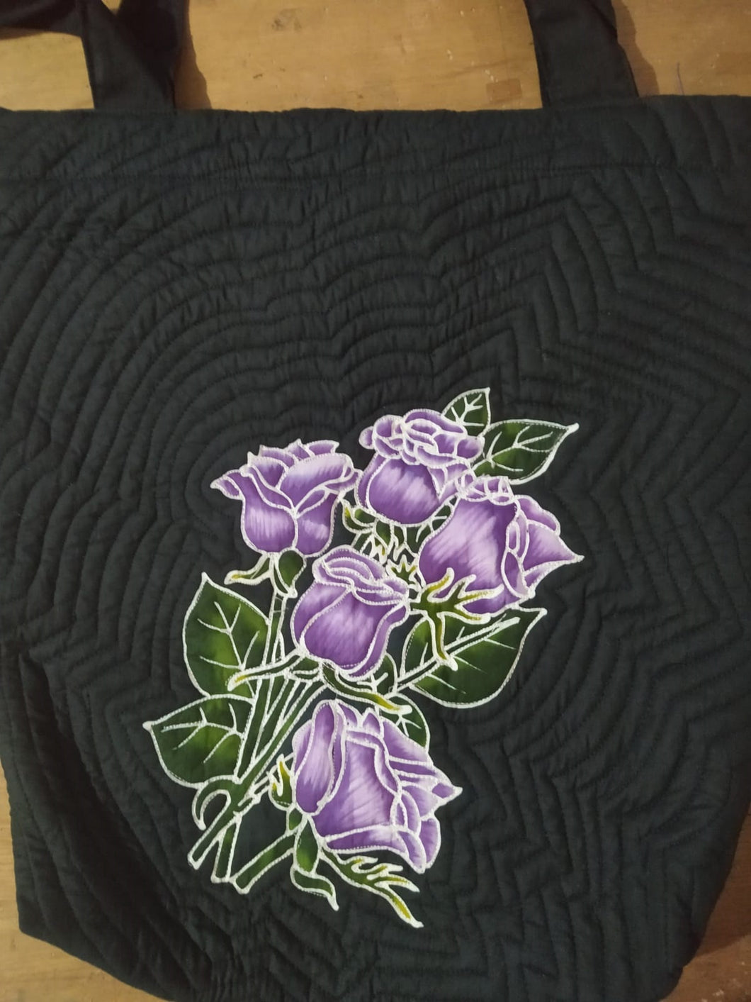 Shoulder bag with a bouquet of lavender roses. The design is handpainted batik. The background color is black.