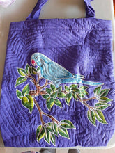 A blue Indian Ringneck parakeet is perching on lush green tropical branches. The design is drawn, batiked, and painted by hand.