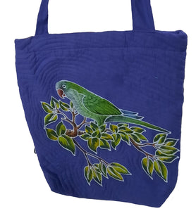 Handpainted batik shoulder bag of a normal (green) Quaker parrot perched among tropical green leaves. This lovely bird is also known as the Monk Parakeet. The bag's background color is blue.