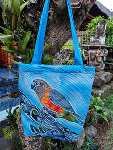A handpainted batik shoulder bag of a lovely Red-bellied parrot perched on a branch. Shades of blue for the background color and the quilting highlights the design.