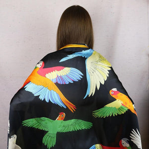 Beautiful parrot-themed evening scarf featuring a variety of parrots. Buttery-soft feel! Large enough to be worn as a shawl. Black background, yellow trim, and lots of colorful parrots!