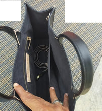 Inside view of the tote-style leather bag. Includes one larger zipper pocked and one open/slit pocket. Cross-body strap included.