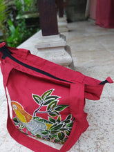 Oblique view of the front and top of the White-bellied caique parrot handpainted batik bag.  The top zipper is evident.