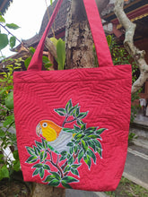 A brightly colored handpainted batik bag featuring a White-bellied caique perched amongst tropical foliage.